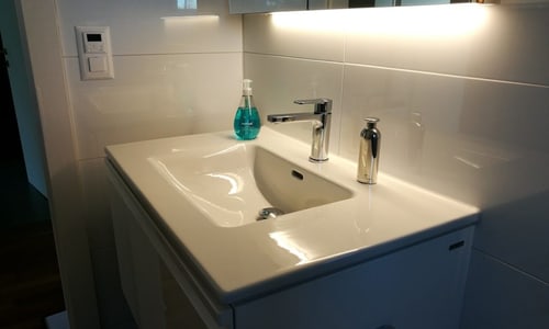 Badezimmer mit weissen glänzenden Platten und weissem Lavabo